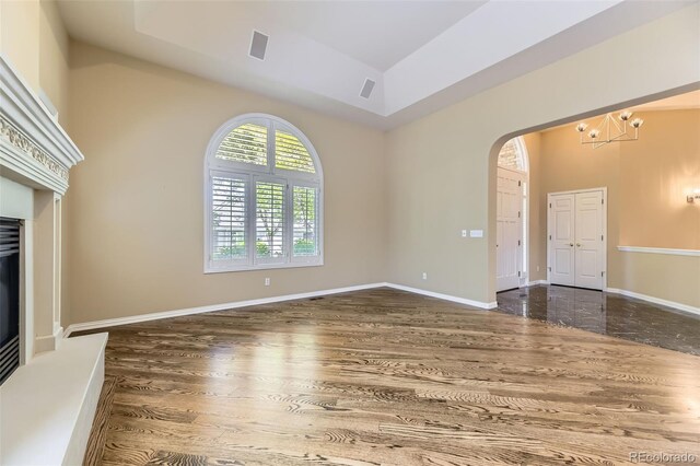 85 Silver Fox Dr, Greenwood Village, CO 80121 - unfurnished living room featuring arched walkways, wood finished floors, a chandelier, and baseboards