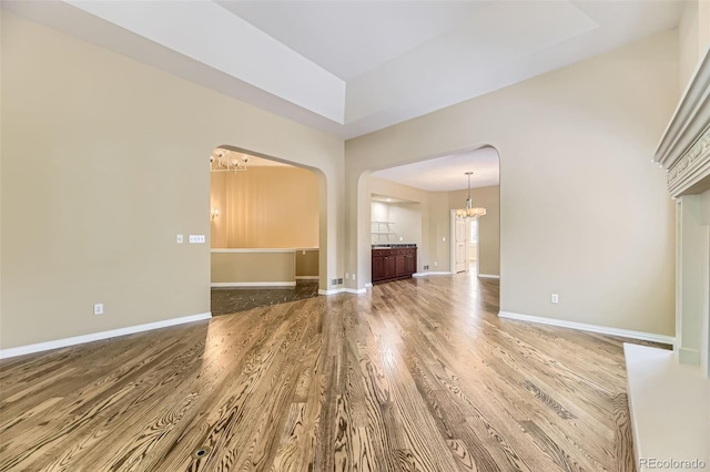 85 Silver Fox Dr, Greenwood Village, CO 80121 - unfurnished living room featuring a chandelier, wood finished floors, arched walkways, and baseboards