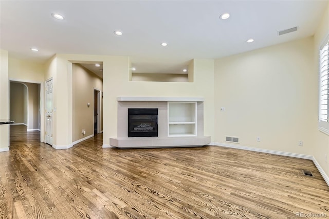 85 Silver Fox Dr, Greenwood Village, CO 80121 - unfurnished living room featuring wood finished floors, baseboards, recessed lighting, a tiled fireplace, and built in shelves