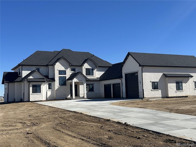 view of front of home with an attached garage, stone siding, concrete driveway, and stucco siding