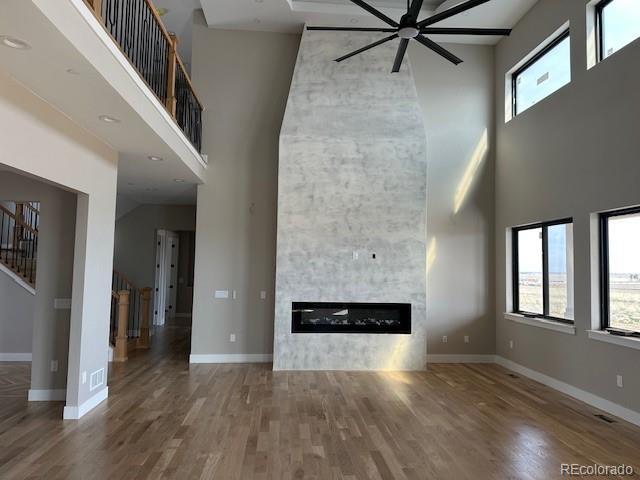 unfurnished living room with a large fireplace, stairway, wood finished floors, and baseboards