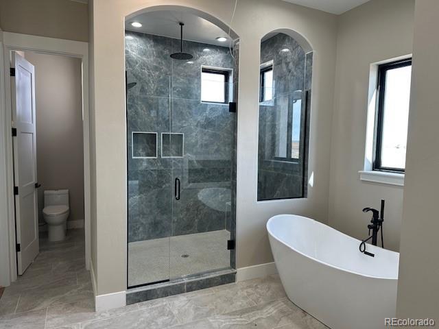 full bath with marble finish floor, a stall shower, plenty of natural light, and a freestanding tub