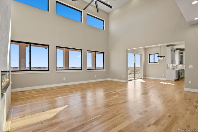 16250 Kenosha St, Brighton, CO 80603 - unfurnished living room featuring visible vents, baseboards, a notable chandelier, and light wood-style flooring