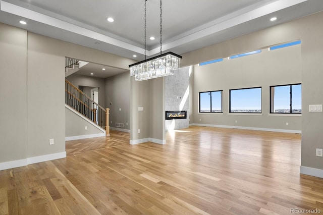 16250 Kenosha St, Brighton, CO 80603 - unfurnished living room with stairway, baseboards, light wood finished floors, recessed lighting, and a glass covered fireplace
