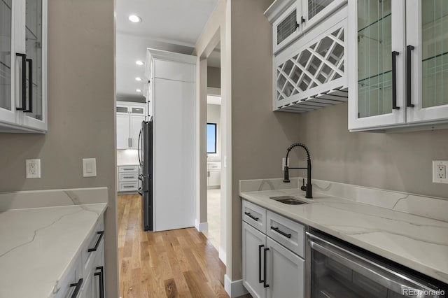 16250 Kenosha St, Brighton, CO 80603 - kitchen with freestanding refrigerator, a sink, wine cooler, white cabinets, and light wood-style floors