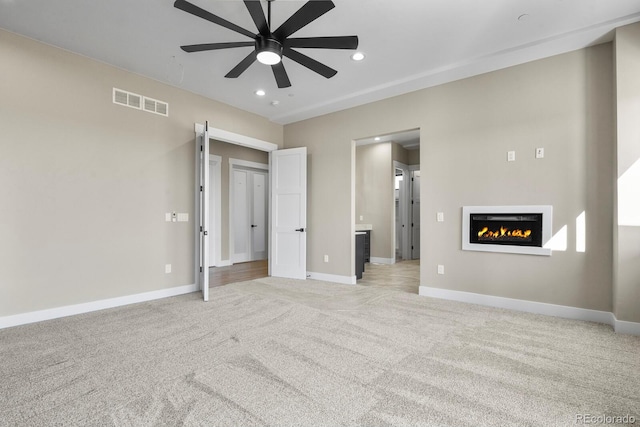 16250 Kenosha St, Brighton, CO 80603 - unfurnished living room featuring baseboards, visible vents, recessed lighting, light carpet, and a glass covered fireplace