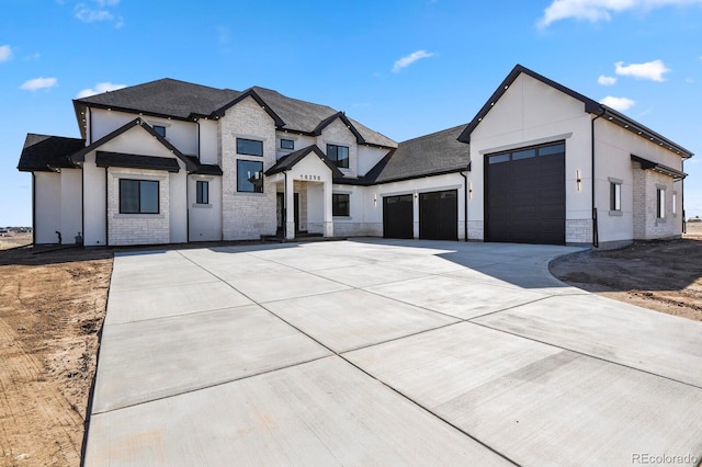 view of front of property featuring concrete driveway, a garage, stone siding, and stucco siding