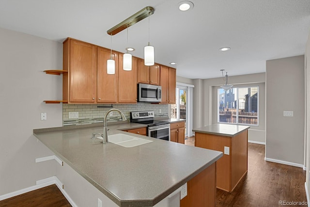 kitchen featuring dark hardwood / wood-style floors, stainless steel appliances, sink, kitchen peninsula, and hanging light fixtures