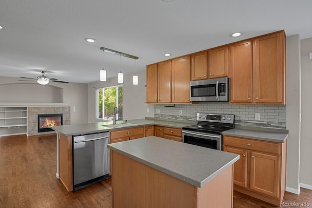 kitchen with sink, kitchen peninsula, a kitchen island, stainless steel appliances, and dark hardwood / wood-style flooring