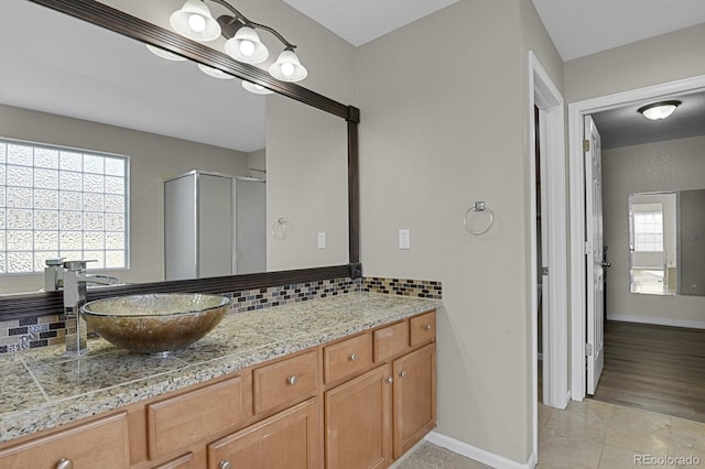 bathroom with hardwood / wood-style floors, walk in shower, vanity, and backsplash