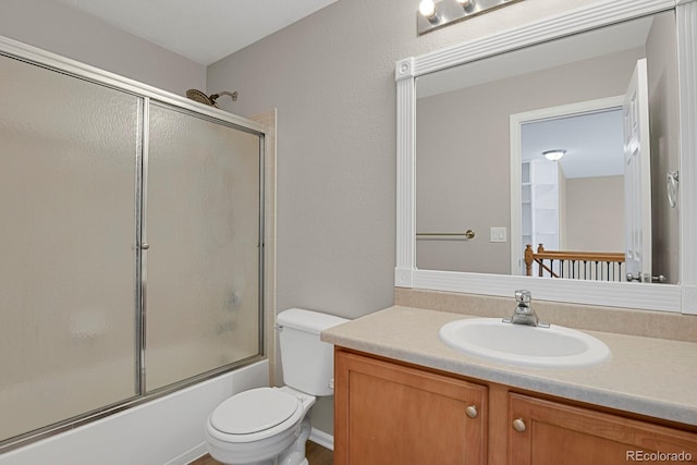 full bathroom featuring combined bath / shower with glass door, vanity, and toilet