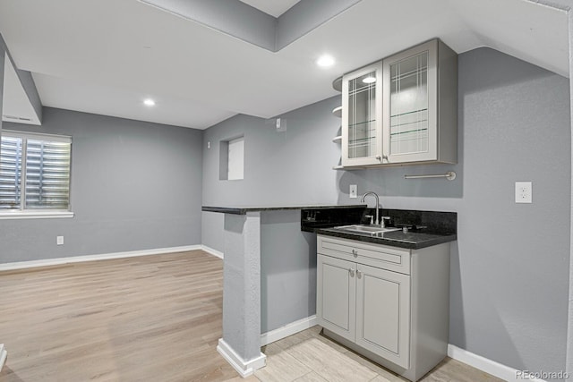 kitchen featuring kitchen peninsula, sink, light hardwood / wood-style floors, and a breakfast bar