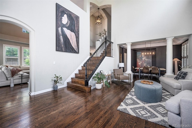 8548 Winter Berry Dr, Castle Pines, CO 80108 - living area featuring wood finished floors, ornate columns, stairway, baseboards, and arched walkways