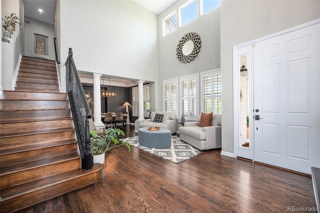 8548 Winter Berry Dr, Castle Pines, CO 80108 - entrance foyer featuring ornate columns, wood finished floors, stairs, a towering ceiling, and baseboards