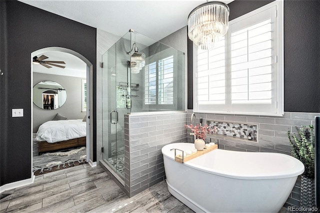 8548 Winter Berry Dr, Castle Pines, CO 80108 - full bath with wood finished floors, ensuite bathroom, a shower stall, tile walls, and a freestanding tub