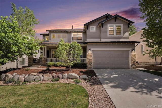 8548 Winter Berry Dr, Castle Pines, CO 80108 - view of front of property featuring concrete driveway, stone siding, an attached garage, a porch, and a front lawn