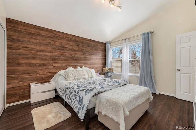 bedroom with dark wood-style floors, vaulted ceiling, wood walls, and baseboards