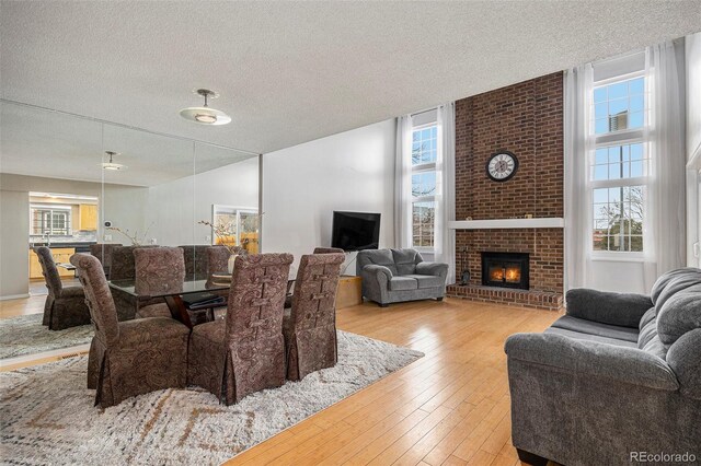 living room with a brick fireplace, a textured ceiling, and hardwood / wood-style floors