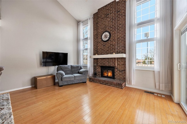 living room featuring high vaulted ceiling, wood-type flooring, and a healthy amount of sunlight