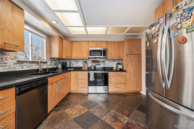 kitchen featuring a sink, stone tile flooring, stainless steel appliances, dark countertops, and backsplash