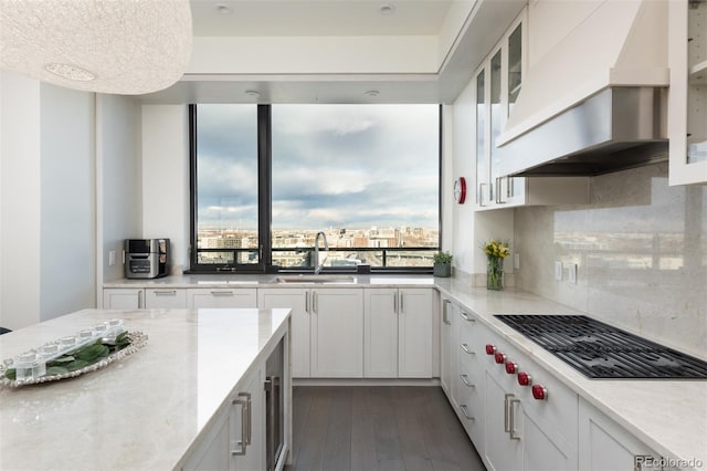 kitchen featuring tasteful backsplash, custom exhaust hood, sink, white cabinetry, and stainless steel gas stovetop