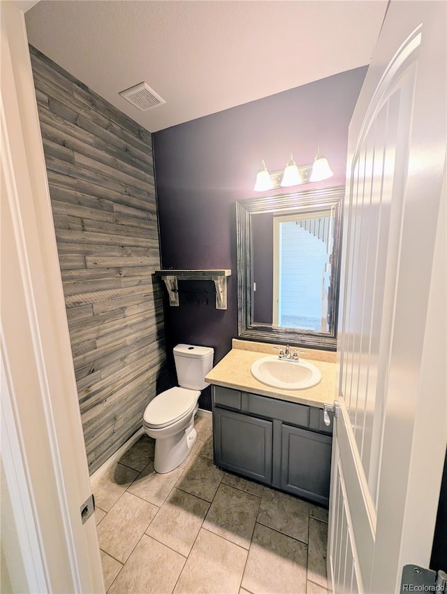 7958 Lightwood Way, Colorado Springs, CO 80908 - bathroom featuring an accent wall, vanity, wooden walls, toilet, and tile patterned flooring