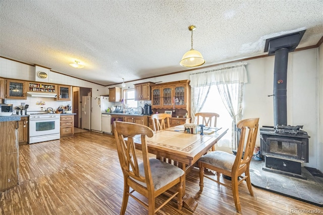 7080 S Calhan Rd, Calhan, CO 80808 - dining area with a textured ceiling, ornamental molding, vaulted ceiling, a wood stove, and light wood-type flooring