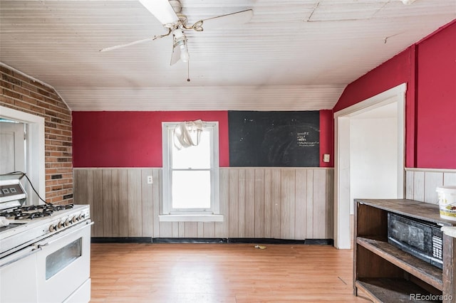 7080 S Calhan Rd, Calhan, CO 80808 - kitchen featuring lofted ceiling, white range with gas stovetop, wainscoting, and light wood-style flooring