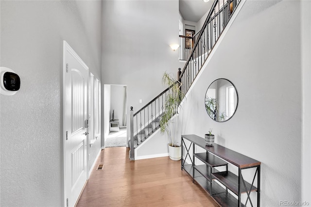 foyer with baseboards, stairway, a high ceiling, and wood finished floors