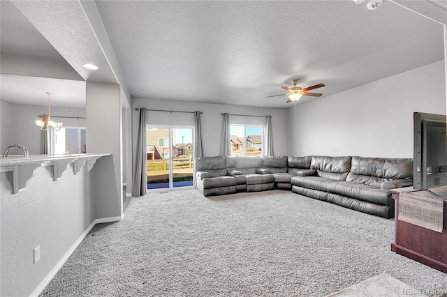 living area with baseboards, a textured ceiling, carpet, and ceiling fan with notable chandelier