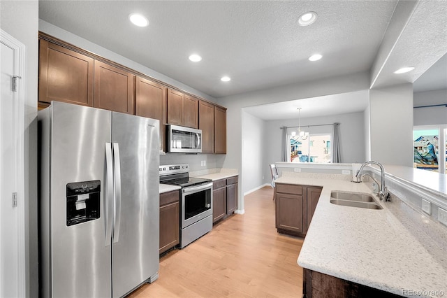 kitchen with a sink, a chandelier, light wood finished floors, recessed lighting, and stainless steel appliances