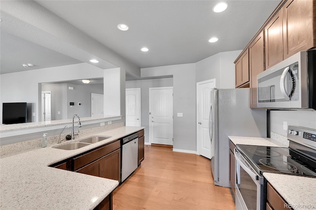 kitchen featuring a sink, recessed lighting, stainless steel appliances, light wood-style flooring, and light stone counters