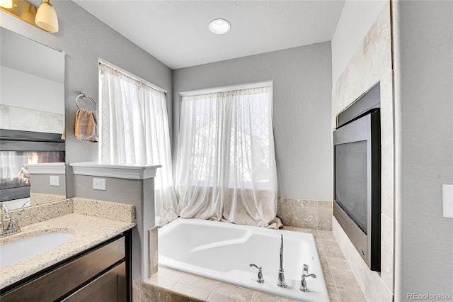 bathroom with a bath, a textured wall, and vanity