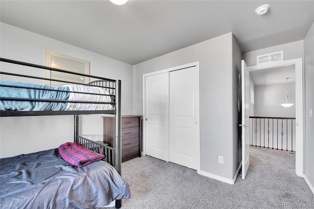 carpeted bedroom with a closet, visible vents, and baseboards