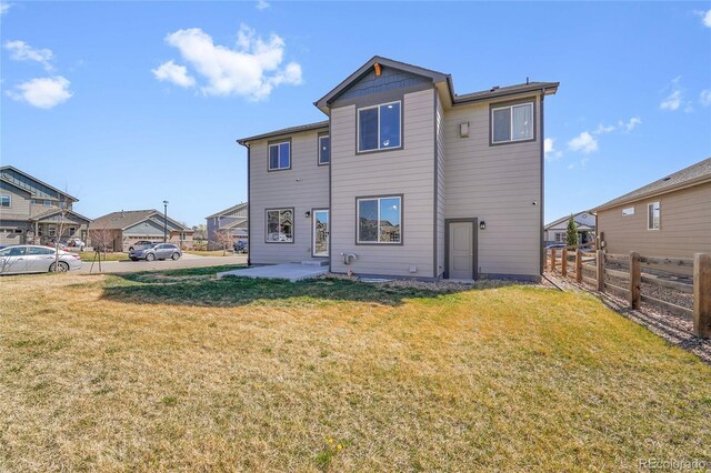 rear view of property featuring a yard, a patio area, and fence
