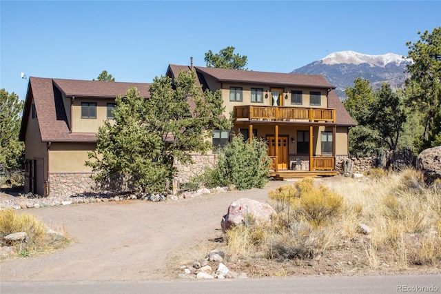 147 Moonlight Way, Crestone, CO 81131 - view of front of home with stone siding, stucco siding, a balcony, a porch, and a mountain view