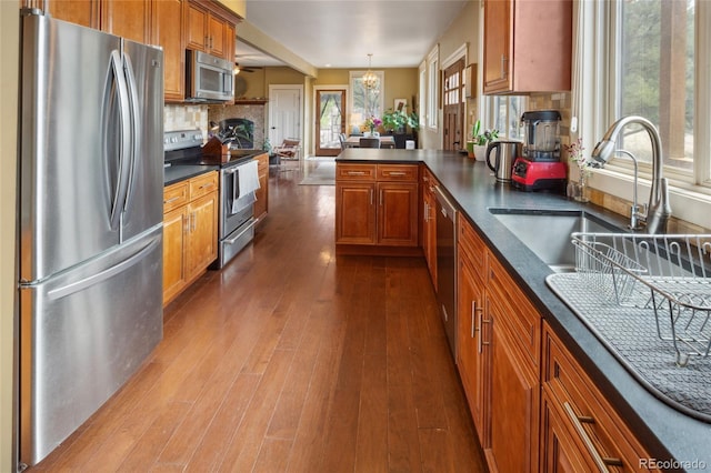 147 Moonlight Way, Crestone, CO 81131 - kitchen with appliances with stainless steel finishes, brown cabinetry, dark countertops, dark wood-style floors, and a sink