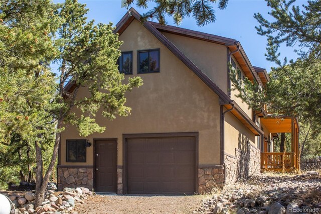 147 Moonlight Way, Crestone, CO 81131 - view of front facade featuring stone siding, an attached garage, and stucco siding