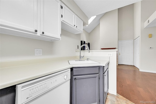 kitchen featuring dishwasher, a sink, light countertops, gray cabinetry, and white cabinets