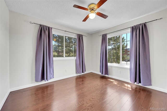 empty room with wood finished floors, a textured ceiling, ceiling fan, and baseboards