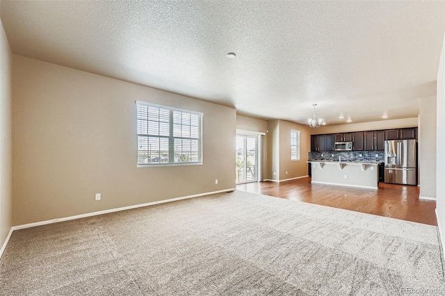 5841 Echo Park Cir, Castle Rock, CO 80104 - unfurnished living room featuring carpet, a chandelier, plenty of natural light, and a textured ceiling