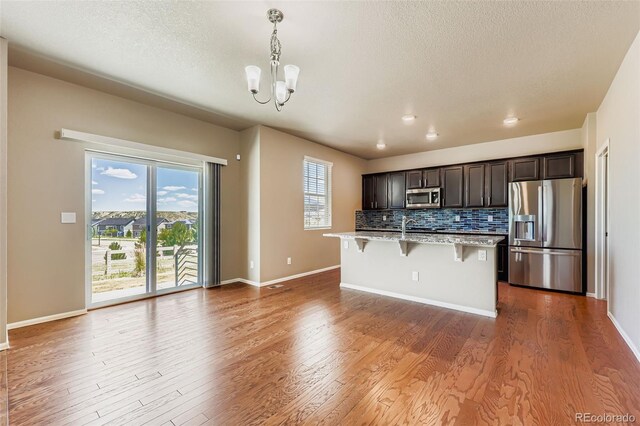 5841 Echo Park Cir, Castle Rock, CO 80104 - kitchen featuring appliances with stainless steel finishes, a chandelier, a breakfast bar area, a textured ceiling, and an island with sink