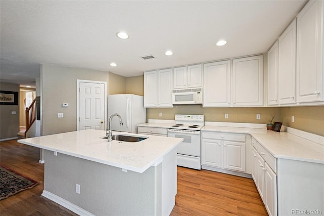 kitchen featuring a sink, white cabinetry, white appliances, and light wood-style floors