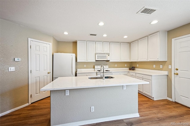 kitchen with a sink, visible vents, baseboards, and white appliances
