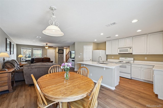 dining space with light wood-type flooring, a ceiling fan, visible vents, and stairway