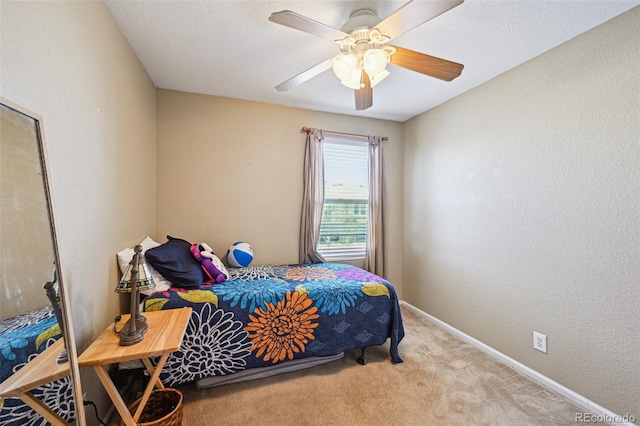carpeted bedroom featuring a textured wall, baseboards, and a ceiling fan