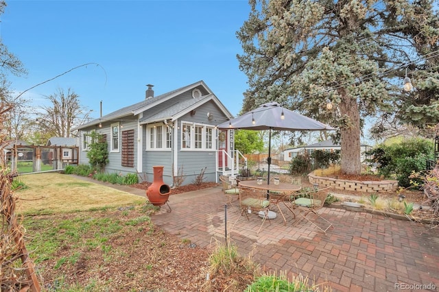 rear view of house featuring a patio area, a yard, and a chimney
