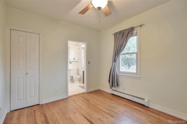 unfurnished bedroom with a baseboard heating unit, light wood-style flooring, baseboards, ensuite bathroom, and a closet