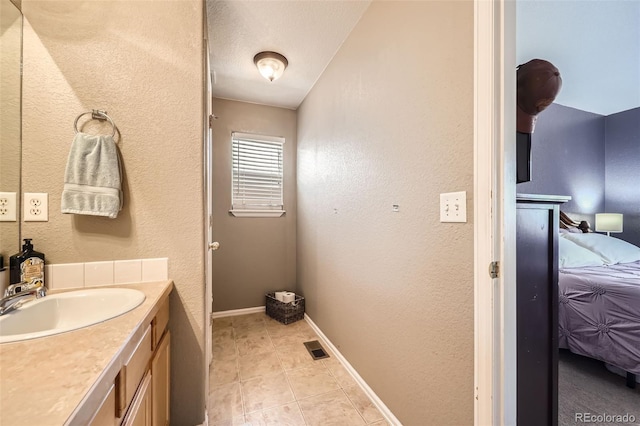 412 Iron St, Brighton, CO 80603 - bathroom featuring ensuite bathroom, vanity, a textured wall, and tile patterned flooring