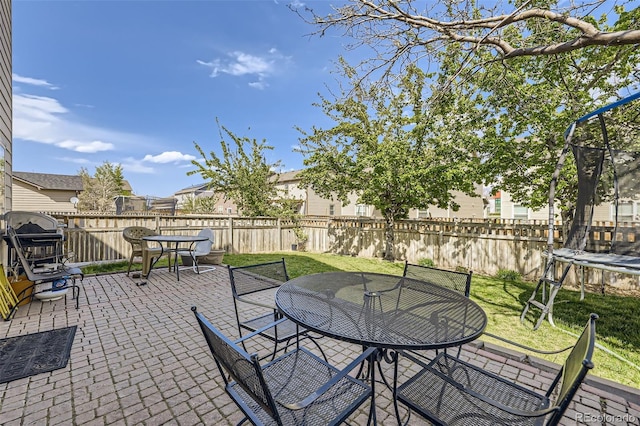 412 Iron St, Brighton, CO 80603 - fenced backyard featuring a trampoline, outdoor dining area, and a patio